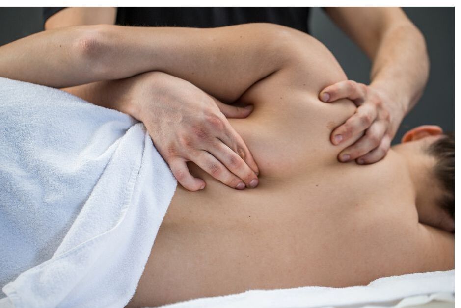 A woman lying on her side while she receives a professional massage on her shoulders and back