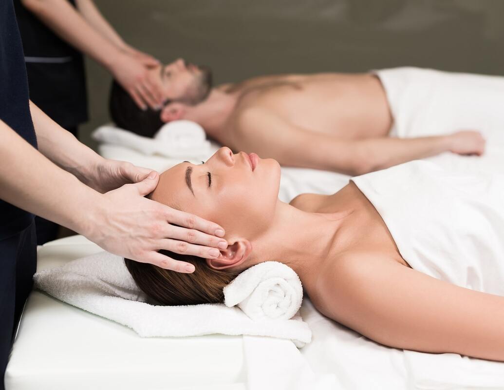 A man and a woman receiving a scalp massage during a couples massage session