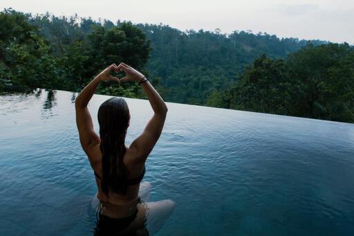A woman doing yoga in a pool overlooking a forest