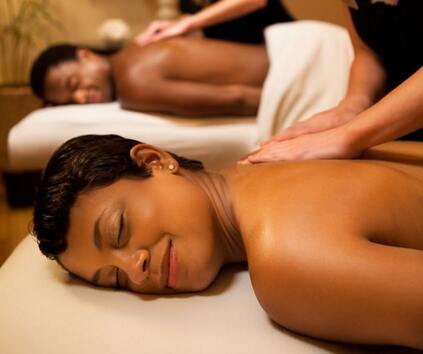 A man and a woman receiving a couples massage side by side