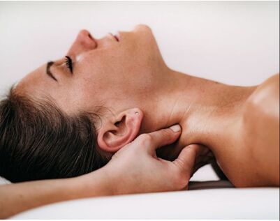 A woman lying on her back and receiving a neck massage