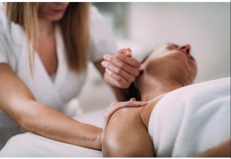 A woman receiving a massage with a neck stretch