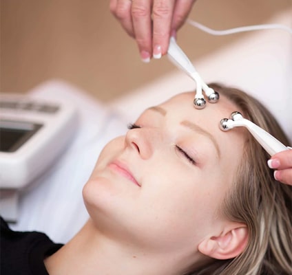 A woman receives a microcurrent facial in a spa