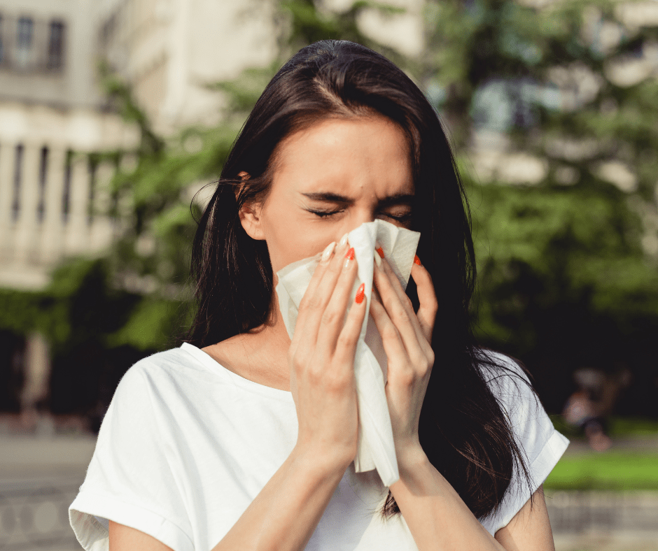 Woman blowing her nose into a tissue due to outdoor allergies